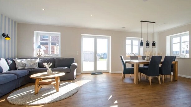 A spacious living room with a sofa, coffee table, and dining area with chairs and a table.