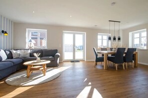 Ein geräumiges Wohnzimmer mit einer Couch, einem Couchtisch und einem Essbereich mit Stühlen und einem Tisch.