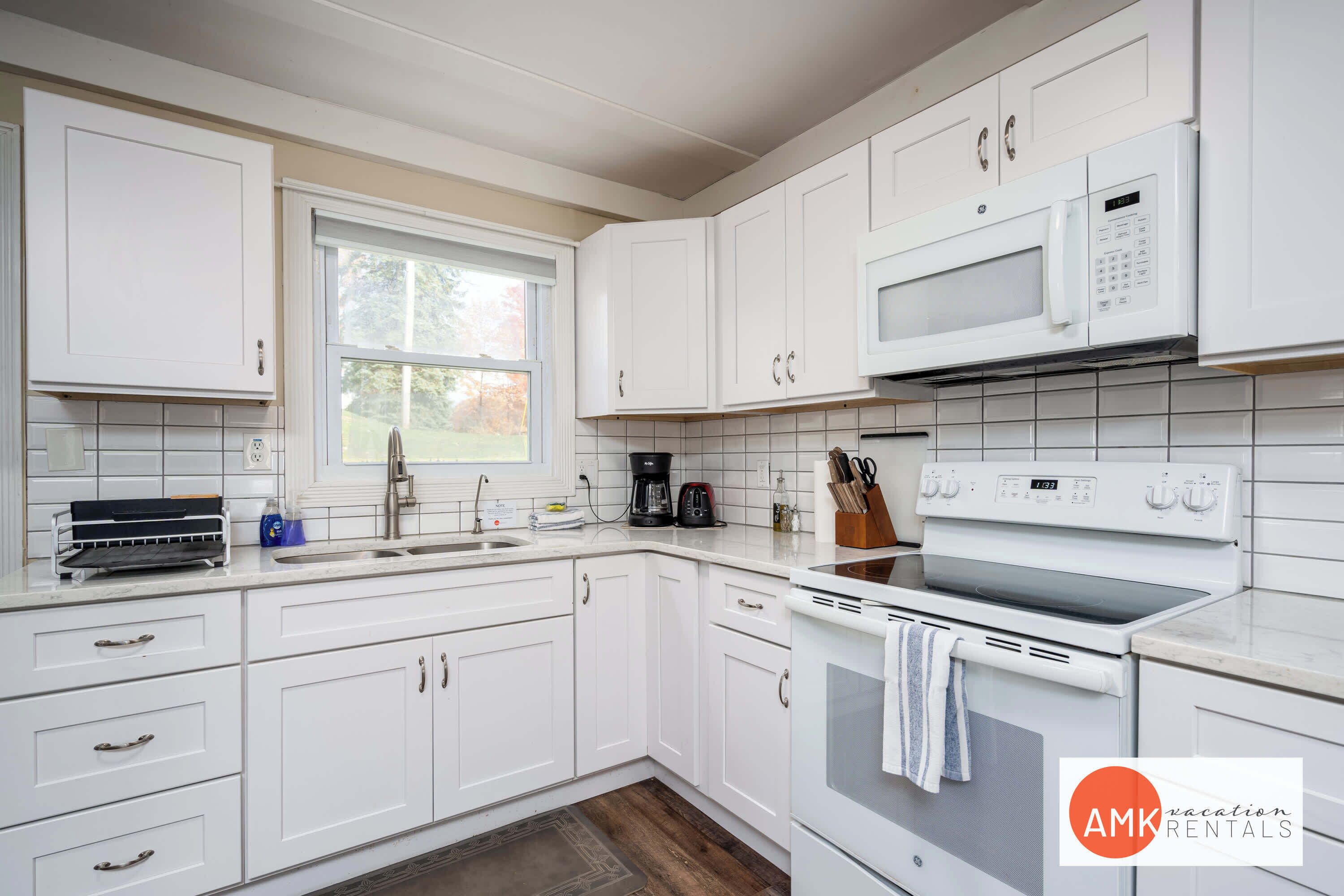 A modern kitchen with white cabinets, a microwave, an oven, and a coffee maker.