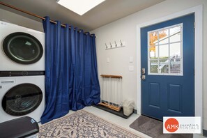 A laundry room with a washing machine, a drying rack, and a blue curtain. - Rest and Relaxation Z's at Slayton Lake (Belding)