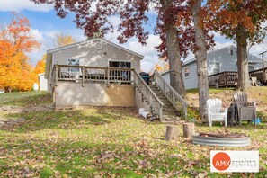 A two-story house with a wooden deck and stairs leading to a porch.