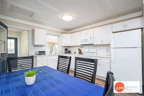 A modern kitchen with white cabinets, a blue table, and a potted plant. - Rest and Relaxation Z's at Slayton Lake (Belding)