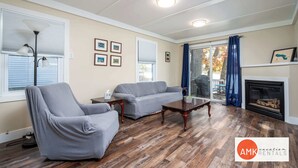 Un salon avec un canapé gris, un fauteuil gris, une table basse en bois et une cheminée.