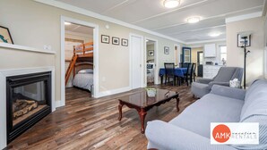 Un vaste salon doté d’un plancher en bois franc, d’une cheminée, d’un canapé, d’un coin repas et d’un escalier menant à un autre niveau.