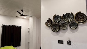 Una camera d'albergo con un letto, una ventola a soffitto, un lampadario a parete e un elemento decorativo appeso al muro.