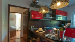 A modern kitchen with red cabinets, a wooden countertop, and a wine bottle.