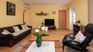 A living room with a sofa, a coffee table with a vase, a TV, and a bookshelf.