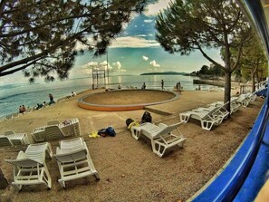 Une plage avec des chaises longues blanches et un espace de détente circulaire.