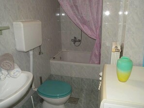 A bathroom with a toilet, a bidet, a bathtub, and a shower curtain. - Serene Garden Apartment With Terrace (Moscenicka Draga)