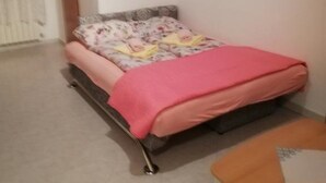 A bedroom with a bed, a small table, and two framed pictures on the wall. - Serene Garden Apartment With Terrace (Moscenicka Draga)