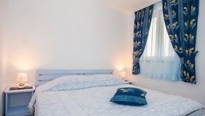A bedroom with a bed, two bedside tables, and a window with curtains. - Charming Brsec Apartment With Shared Pool (Moscenicka Draga)