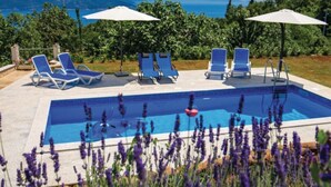 A swimming pool with blue water, surrounded by lounge chairs and umbrellas, set against a backdrop of mountains and greenery. - Charming Brsec Apartment With Shared Pool (Moscenicka Draga)