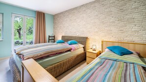 A bedroom with two beds, a brick wall, and a window with curtains. - Apartment 'Untere Ferienwohnung' with Private Terrace, Shared Garden and Wi-Fi (Meßstetten)