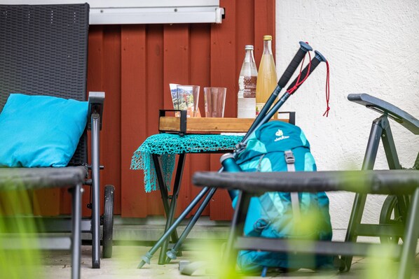 Una zona patio con mobili da esterno, un tavolo con tovaglia all'uncinetto, uno zaino blu e una bicicletta.