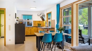 A modern kitchen with wooden cabinets, a built-in stove, and a dining area with blue chairs and a table. - Apartment 'Untere Ferienwohnung' with Private Terrace, Shared Garden and Wi-Fi (Meßstetten)