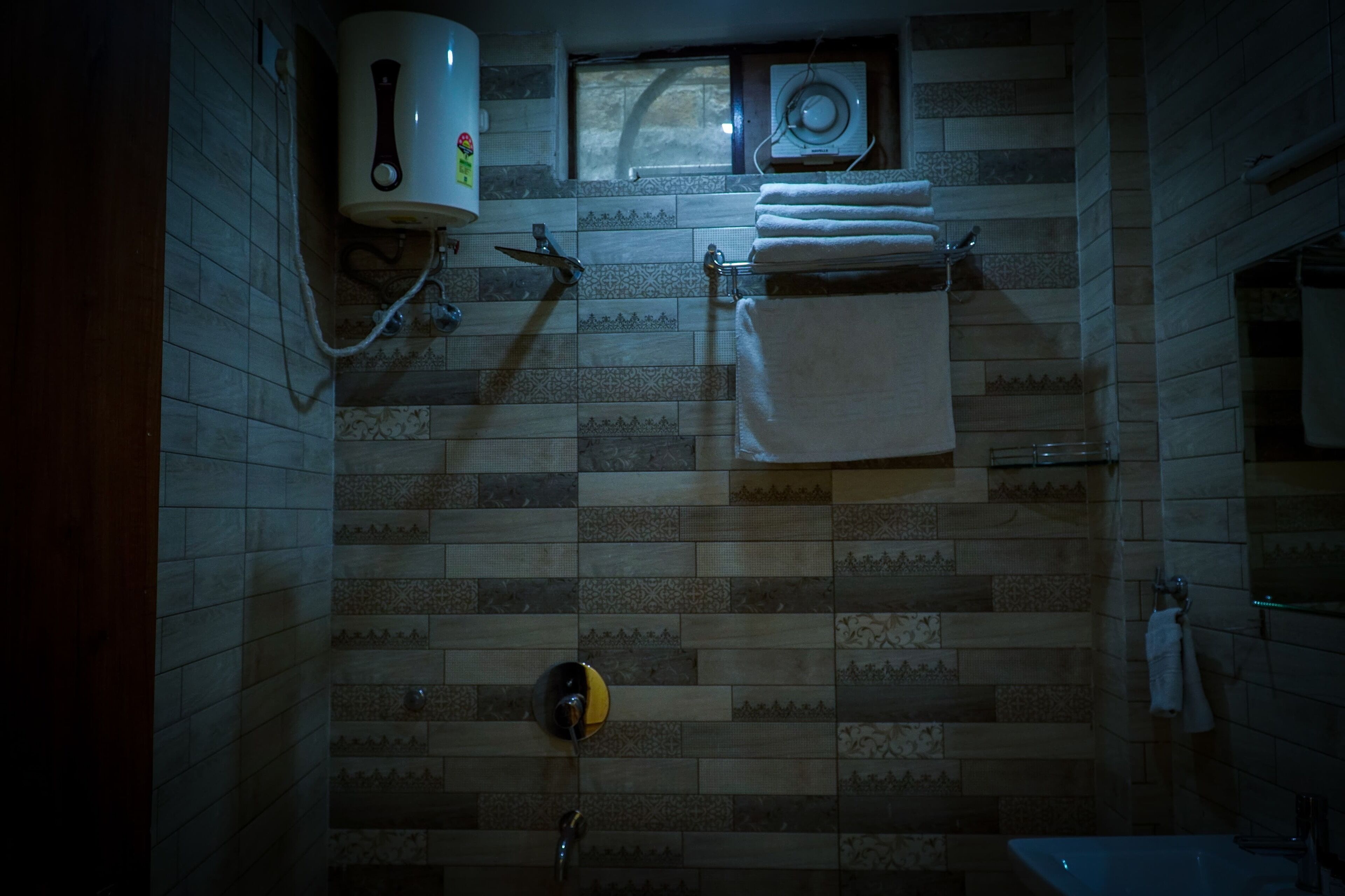 A bathroom with patterned tiles, a towel rack, a toilet, and a shower.