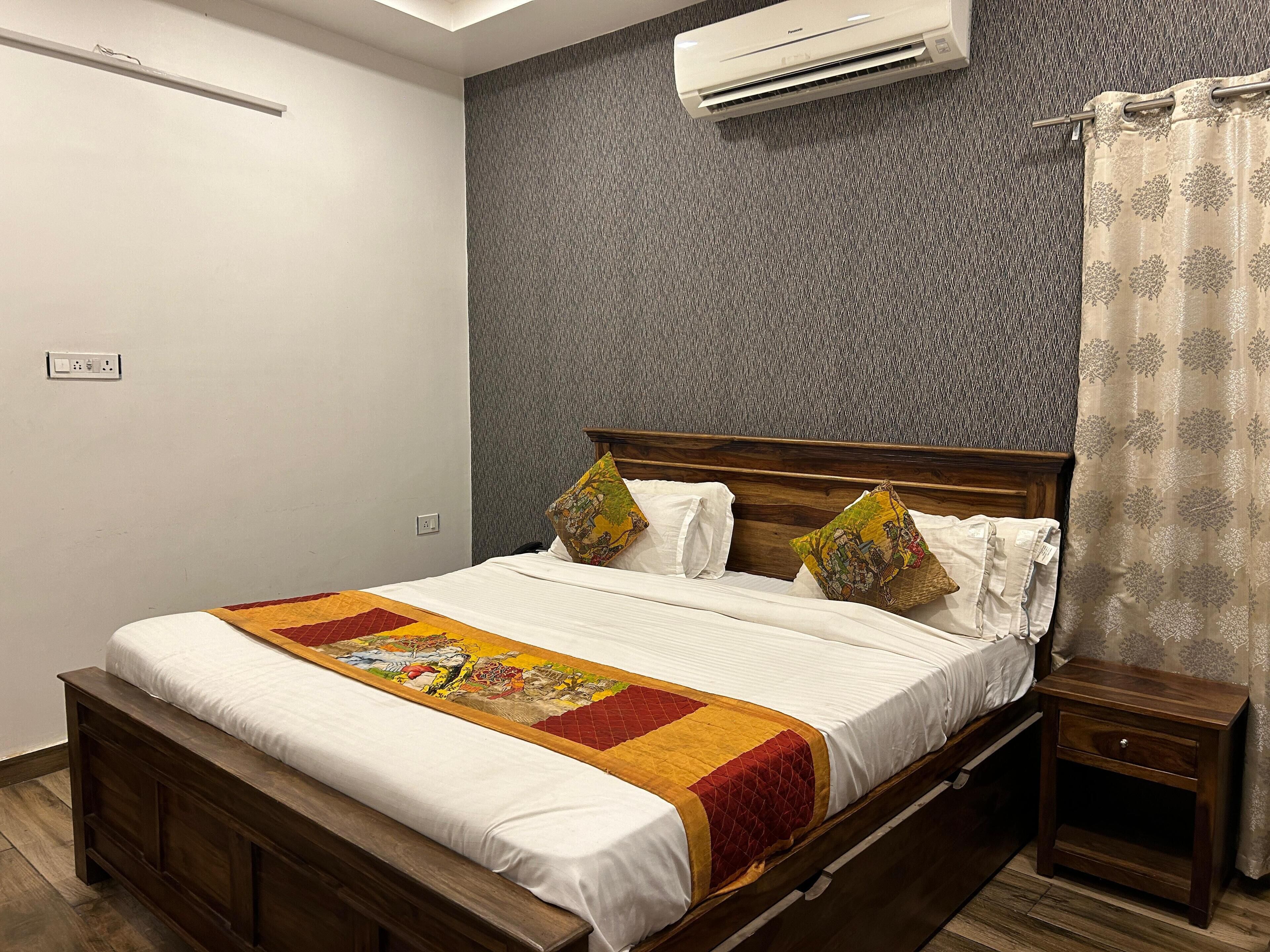 A neatly made bed with a colorful quilt, a wooden headboard, and a bedside table with a drawer.