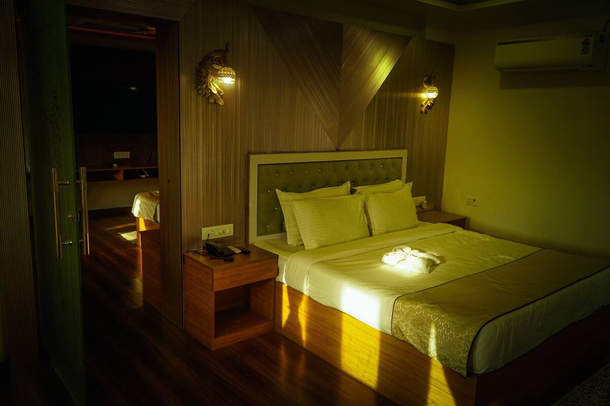 A hotel room with a bed, bedside tables, and wall-mounted lamps.