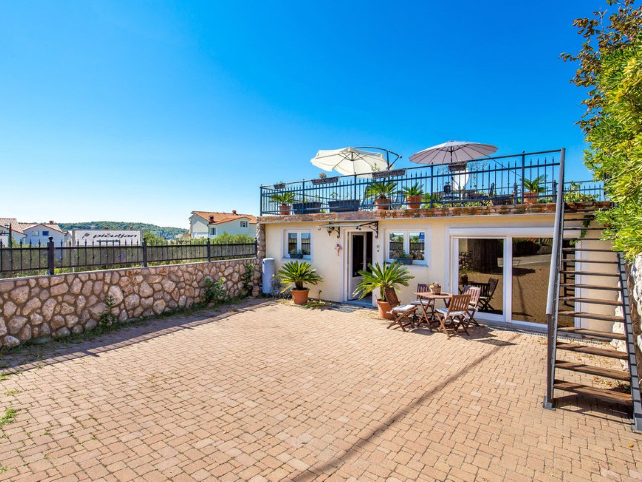 A two-story house with a patio area, outdoor furniture, and potted plants.