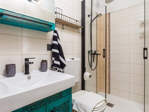 Un baño moderno con un lavamanos blanco, cabina de ducha y un perchero para toallas.