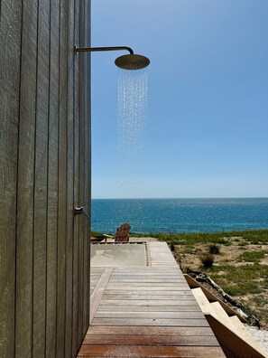 A wooden door with a showerhead, a wooden deck leading to a beach view. - Nora - Tiny Coastal Sanctuary with Panoramic Ocean Views, Off-grid Beachfront Cabin on Kangaroo Isla... (North Cape)