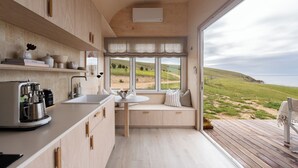 A modern kitchen with a built-in seating area, a large window with a view of the beach, and a ceiling fan.