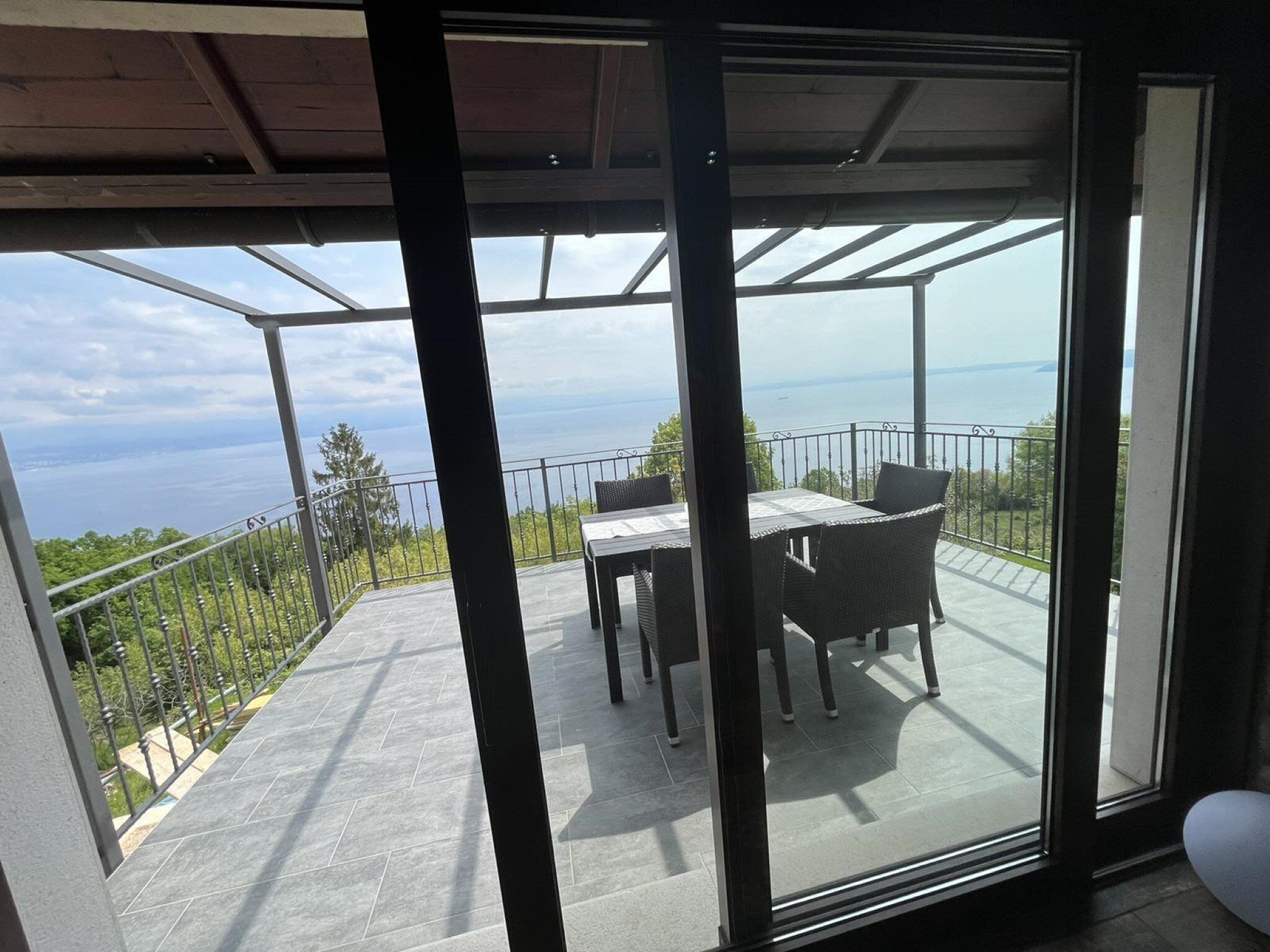 Un balcón con mesa y sillas, con vistas panorámicas al mar y la vegetaci ón.