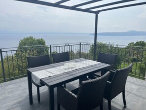 Una terraza con mesa y sillas, con vistas a un cuerpo de agua y vegetación.