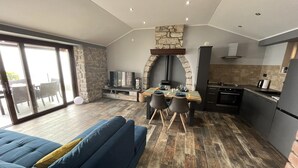 A modern kitchen with a stone arch, a dining area with a table and chairs, and a blue sofa in a spacious living area with large windows. - Splendid Holiday Home With Panoramic Sea Views Moscenicka Draga (Moscenicka Draga)