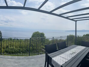 An outdoor patio with a table and chairs, overlooking a body of water and greenery. - Splendid Holiday Home With Panoramic Sea Views Moscenicka Draga (Moscenicka Draga)