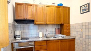 Een keuken met houten kastjes, een ingebouwde oven, een koffiezetapparaat en een spoelbak.