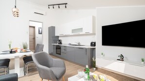 A modern kitchen with white cabinets, a grey chair, and a dining table with chairs. - Stylish Two Bedroom Apartment in Labin (Labin)