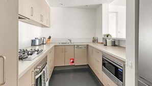 Une cuisine moderne équipée d’appareils électroménagers en acier inoxydable, d’un lave-vaisselle et d’un four à micro-ondes.