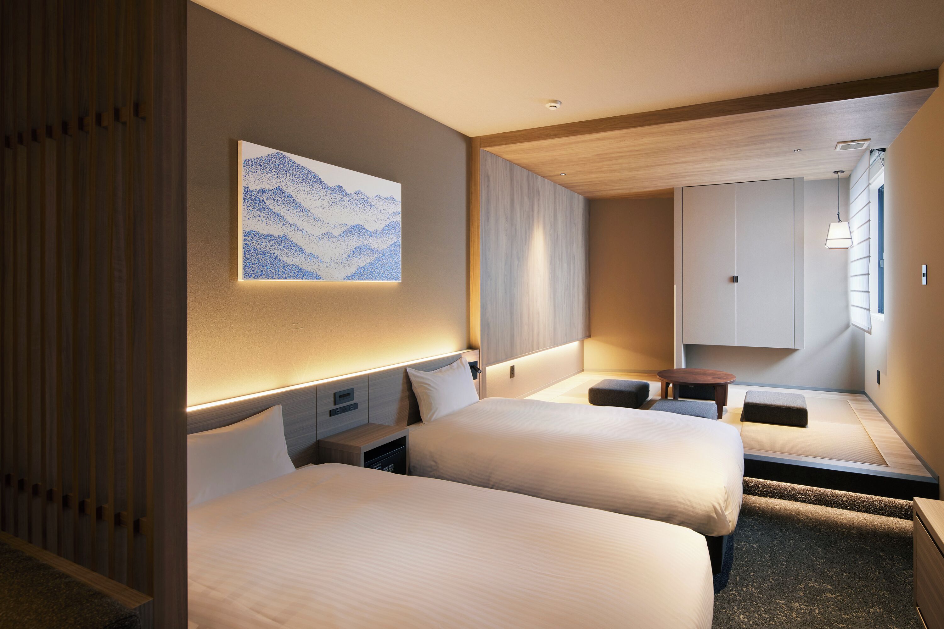 A hotel room with two beds, a small table, and a seating area.