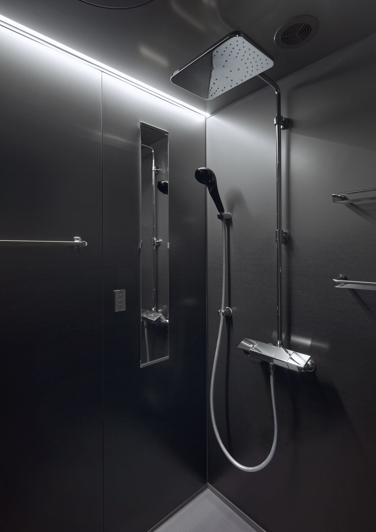 Una ducha moderna con cabezal de ducha manual, panel de control en la pared y un accesorio de ducha de mano.