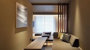 Un interior moderno con un sofá, una mesa de madera y vistas a un paisaje urbano a través de amplios ventanales.
