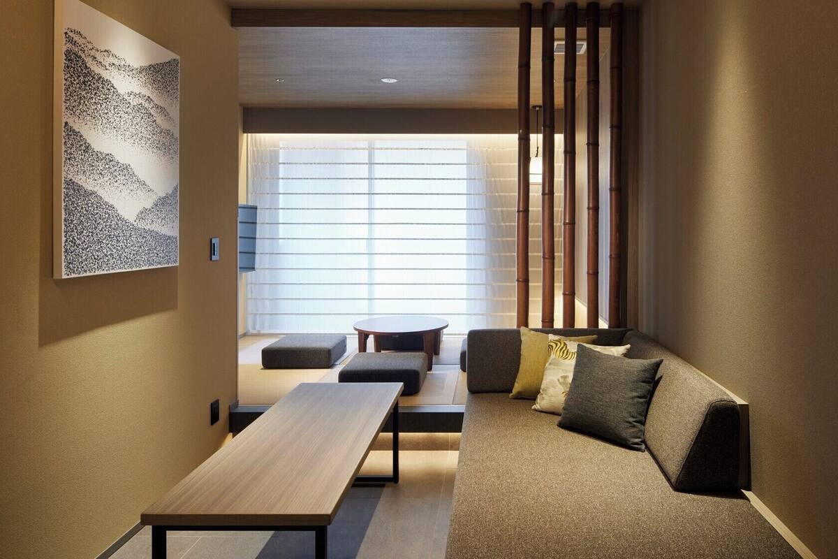 Un interior moderno con un sofá, una mesa de madera y vistas a través de un ventanal.