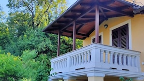 A two-story building with a balcony, columns, and a wooden roof.