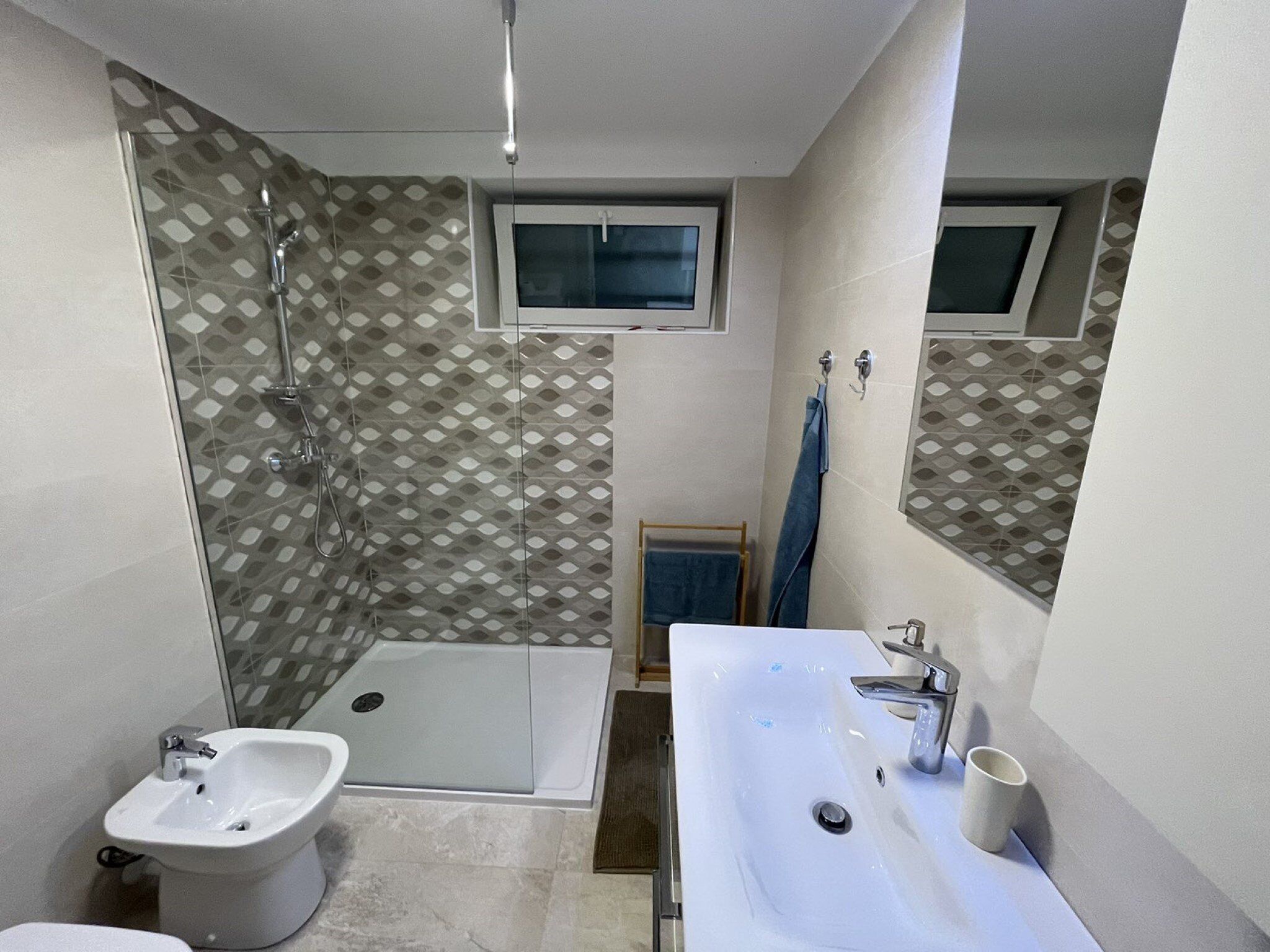 A bathroom with a shower, bidet, and a large sink.