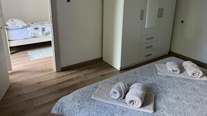 A bedroom with a bed, a wardrobe, and a small bedside table.
