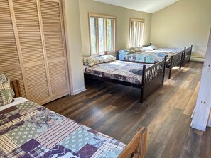 A bedroom with two beds, wooden flooring, and a large closet.