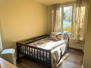 A bedroom with a wooden bed, a window with curtains, and a radiator. - Heated Indoor Private Pool | Stream Front | Game Room (Cresco)