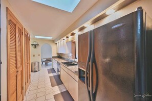A modern kitchen with a stainless steel refrigerator, wooden cabinets, and a skylight. - Heated Indoor Private Pool | Stream Front | Game Room (Cresco)