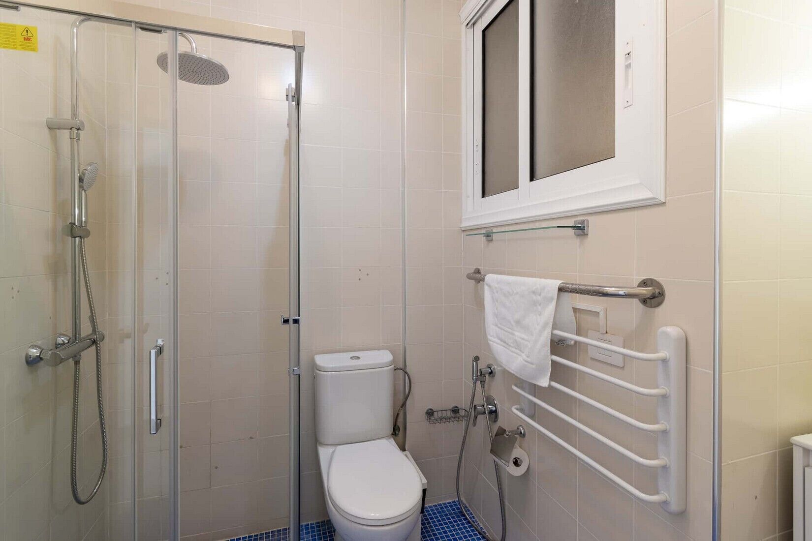 A small bathroom with a shower, toilet, and a window.