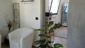 A living room with a white armchair, a potted plant, and a decorative metal panel on the wall. - LaBandaBassottiFerrara  (Monestirolo)