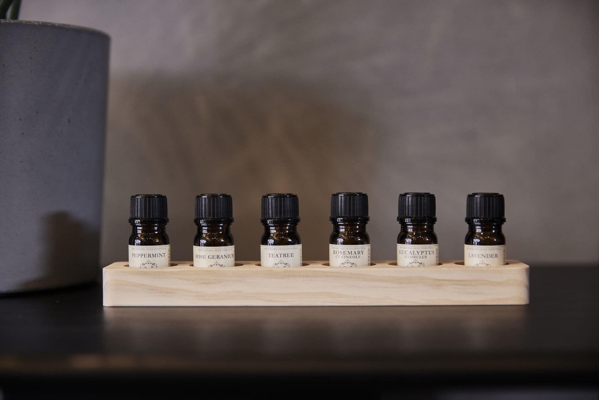 A wooden tray holding six small bottles of essential oils.