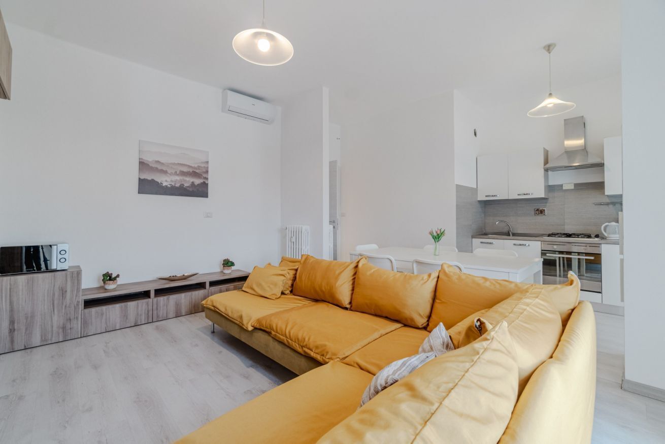 Una sala moderna con sofá, una mesa de comedor y una zona de cocina.