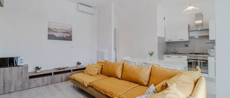 Una sala moderna con sofá, una mesa de comedor y una zona de cocina.