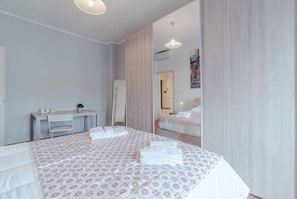 Una camera d'albergo con un letto, una scrivania, una sedia, uno specchio e una porta.