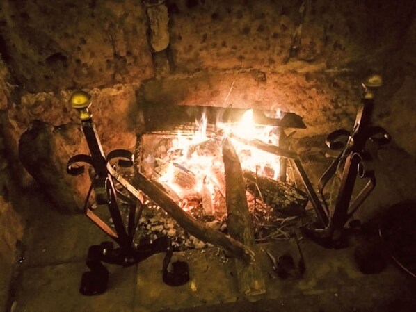 Una chimenea con leña y fuego encendido en una pared de piedra.